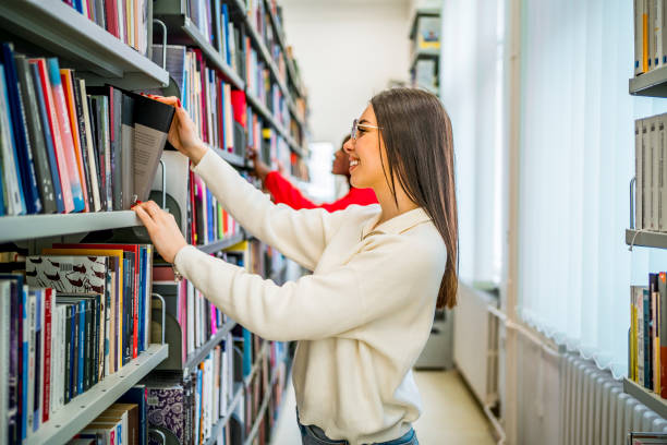 istock Young female student choosing a book in the library 1474897782