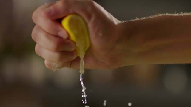 hand squeezing lemon in slow motion