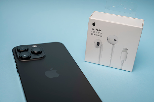 New iPhone 14 pro max and Apple Earpods, Airpods white earphones for listening to music and podcasts, in a closed box. Isolated blue background. Budapest, Hungary - February 16, 2023