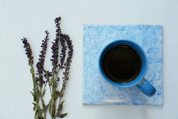 istock Cup of aromatic herbal tea and sage flowers on white table, flat lay 1474901602