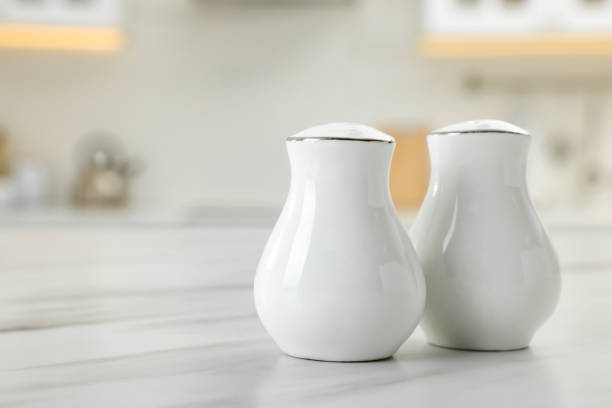 istock Ceramic salt and pepper shakers on white marble table in kitchen. Space for text 1474901643