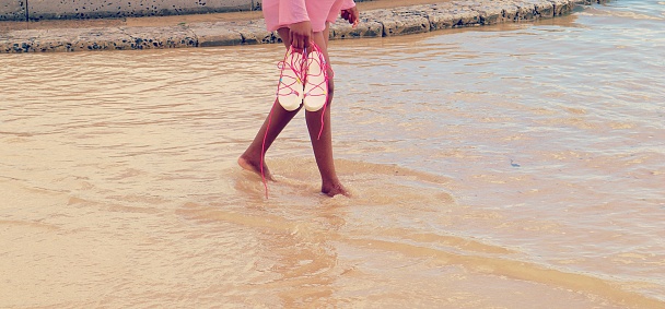 woman legs walking in water on the beach