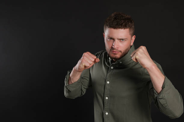istock Young man ready to fight on black background, space for text 1474902700