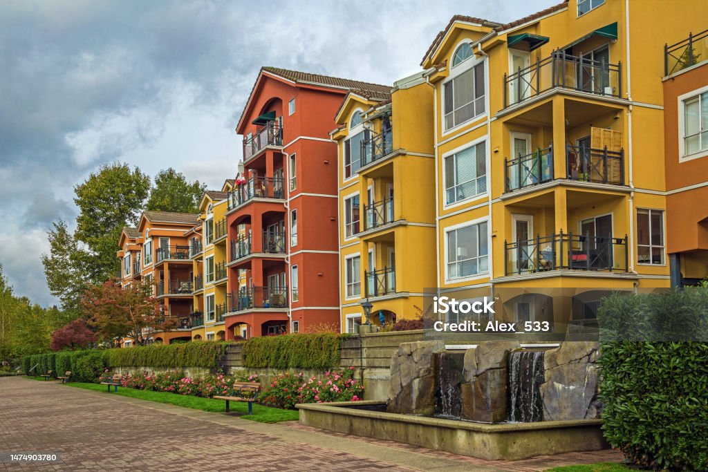 Residential District in Downtown of New Westminster Residential complex in Downtown of New Westminster City with pond in the yard , orange and yellow buildings with flowerbed and green bushes at the front Apartment Stock Photo