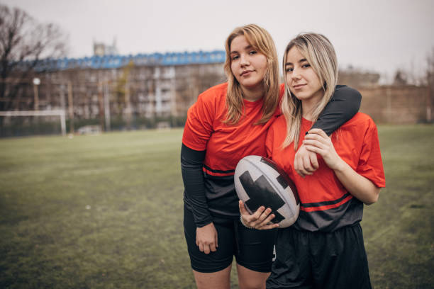 Teenage girls rugby players on rugby field together outdoors.