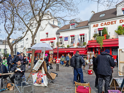Paris, France - 6 March, 2023: People walking in the Montmartre neighborhood. The traditional district is famous by its artists, cafes, restaurants and nightlife.