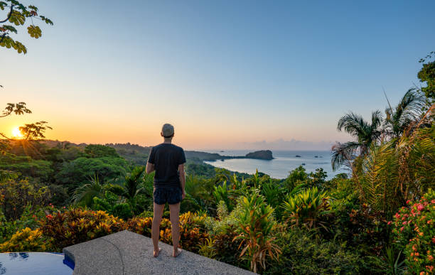 Woman Enjoying a Vibrant Sunrise over the Wild Untamed Coastal Beauty of Manuel Antonio National Park on the Pacific Coast of Costa Rica stock photo