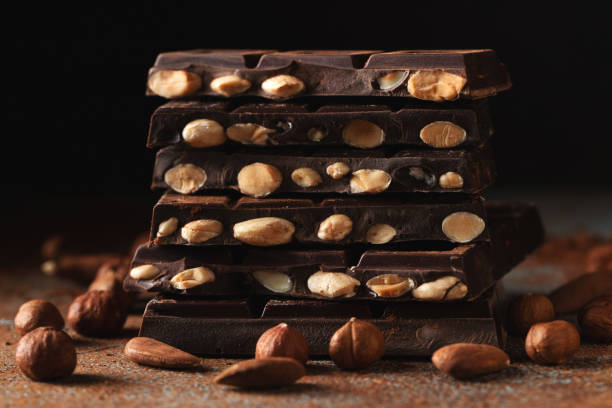 istock Dark and milk chocolate with nuts on a dark background sprinkled with cocoa powder. 1474912457