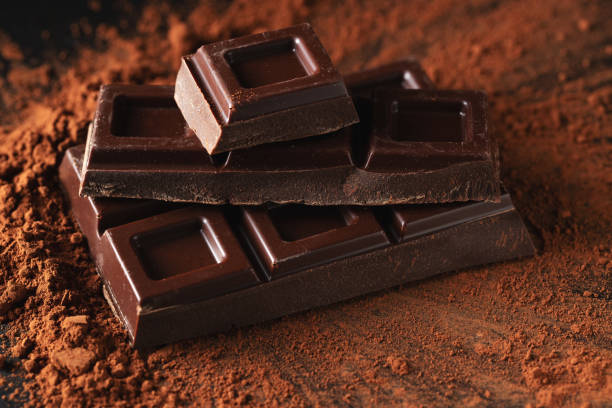 istock Dark and milk chocolate with nuts on a dark background sprinkled with cocoa powder. 1474912468