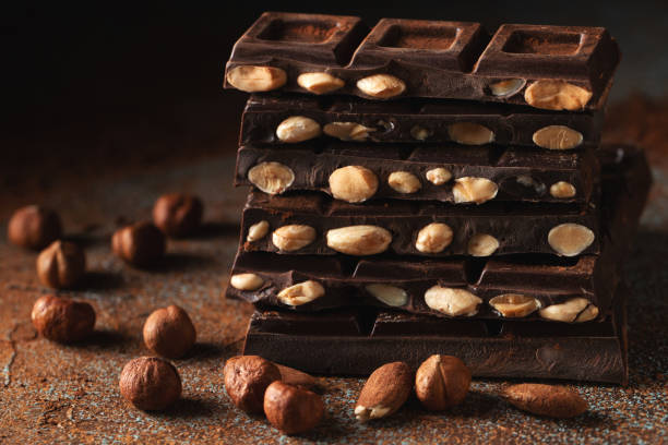 istock Dark and milk chocolate with nuts on a dark background sprinkled with cocoa powder. 1474912473