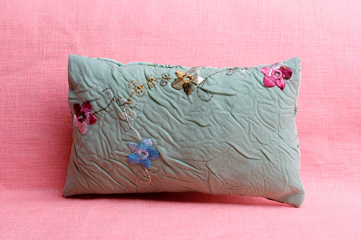 Green cushion with flower pattern on pink background