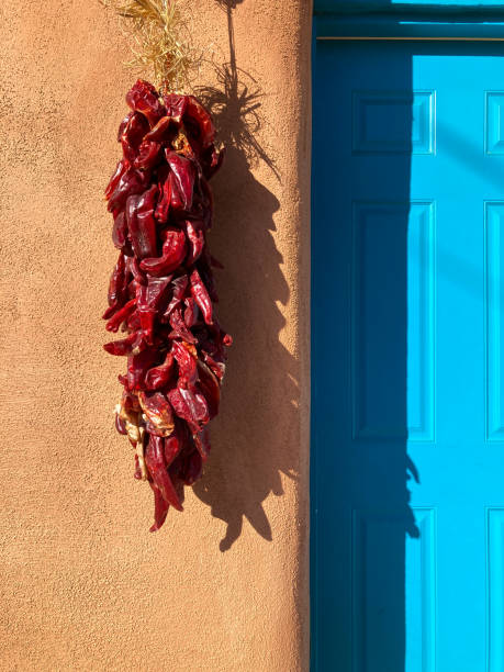 santa fe, nm: sunlit chili pepper ristra, adobe wall, niebieskie drzwi - ristra zdjęcia i obrazy z banku zdjęć