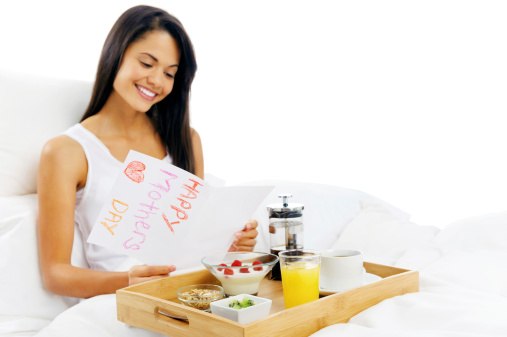 Happy mothers day breakfast in bed mum is happy and smiling, reading a card in the morning