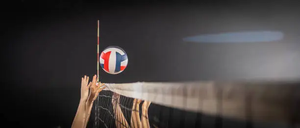 Female athletes hands throwing volleyball ball through net side view