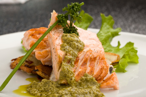 photo of delicious grilled salmon with green basil sauce and vegetables