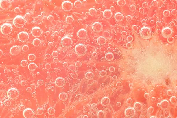 Slice of grapefruit in sparkling water. Grapefruit slice covered by bubbles in carbonated water. Grapefruit slice in water with bubbles stock photo