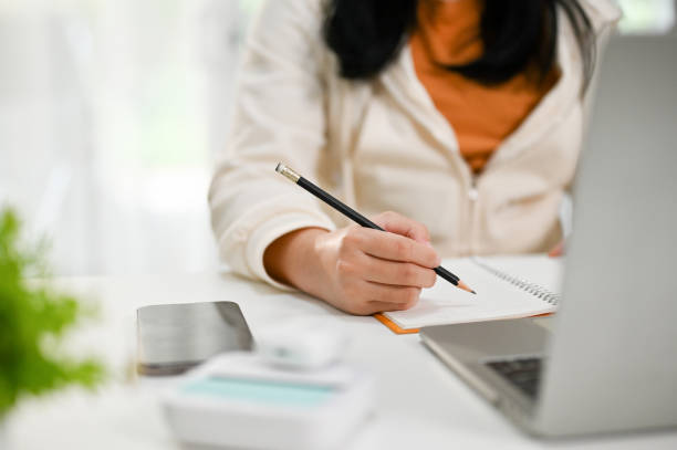 istock Cropped image of an Asian female college student doing homework, writing something 1474940918