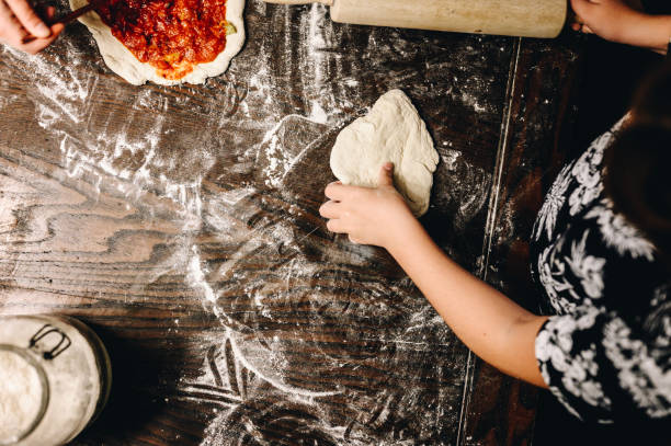 istock Family making pizza at home together at the kitchen table, hands from above 1474941106