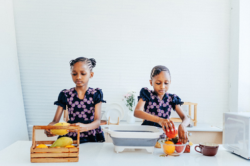 Twin girls washing fruit in the kitchen