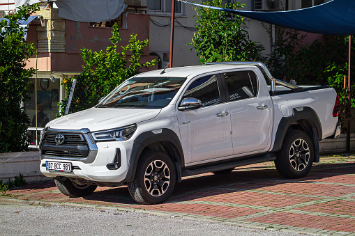 Side, Turkey - February 05, 2023:  white Toyota Hilux parked on the street on a warm summer day against the backdrop of  park