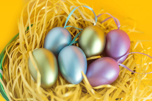 Multi-colored Easter eggs in a nest on a festive orange background. The minimal concept of Easter. top view. Easter card with a copy space for text.