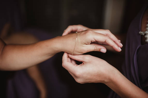 One woman helping another with jewelry