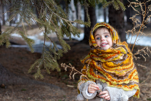 Cute little girl singing in the forest in warm clothing