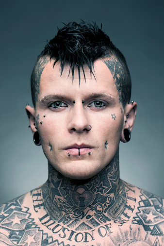 Portrait of a young man with a lot of tattoos and piercings