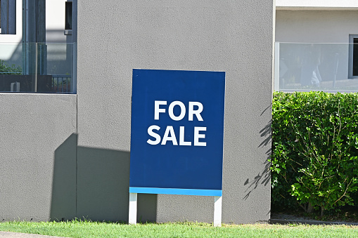 Blue and white for sale sign in front of a property