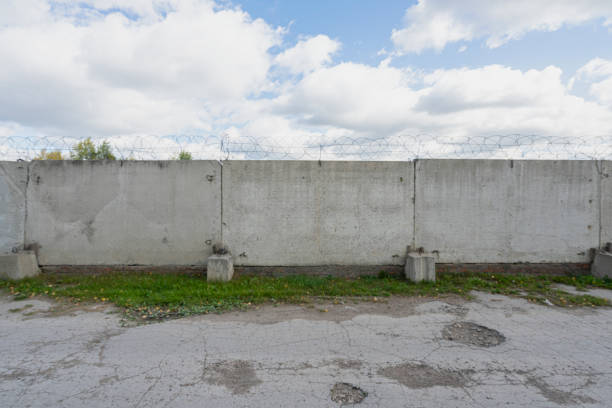 Concrete fence with metal barb construction on blue sky background. High quality photo
