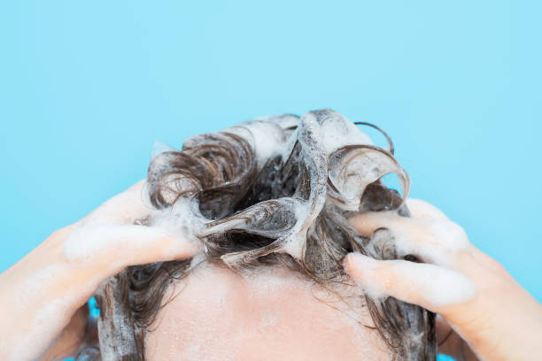 istock A girl washes her hair with shampoo on blue background, front view. 1474963368