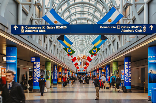 Chicago, Illinois, United States - May 5, 2016: Travelers at Chicago O'Hare International Airport which is the primary airport serving the Chicago area. O'Hare is the one of the busiest airport in the world. The roof steel structure with glass allow sunlight to illuminate the main hallway.