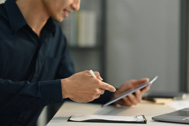 istock Millennial businessman using digital tablet working online or browsing internet, enjoying modern technologies at workplace. 1474968643