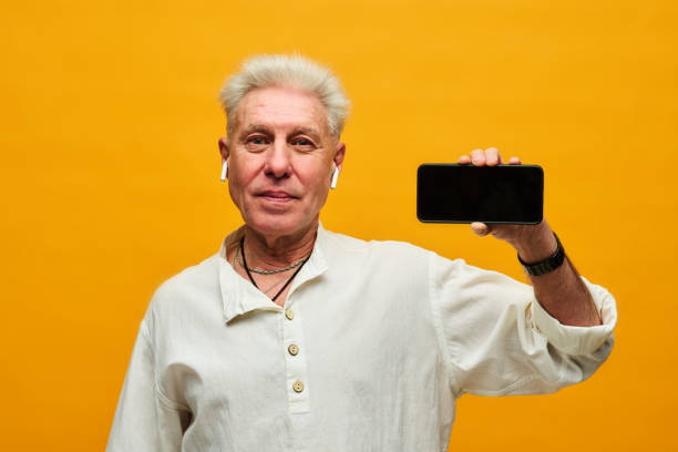 istock Mature man with grey hair holding smartphone with blank screen 1474971455