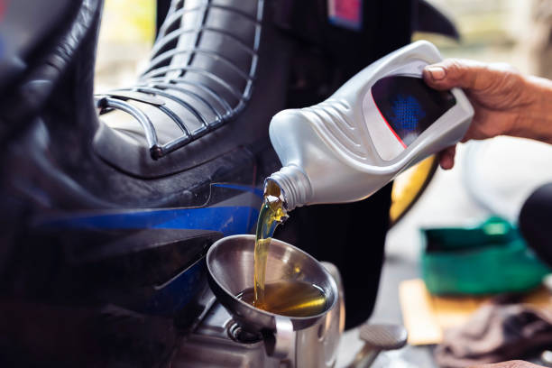 el mecánico está reemplazando una nueva botella de lubricante por una motocicleta. - motor oil bottle fotografías e imágenes de stock