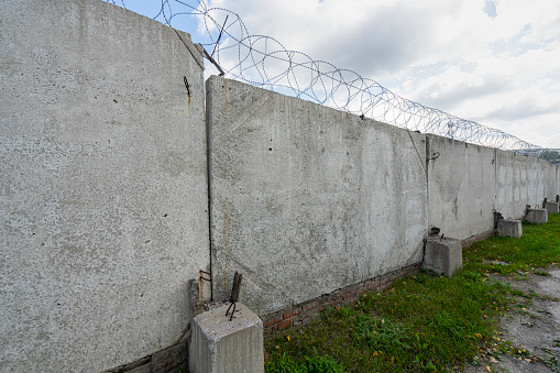 Concrete fence with metal barb construction on blue sky background. High quality photo