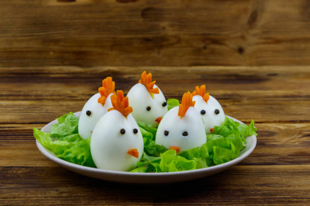 Funny easter breakfast with boiled eggs as chicks on wooden table stock photo