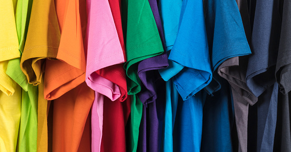 Colorful t-shirts hanging on a rack, background