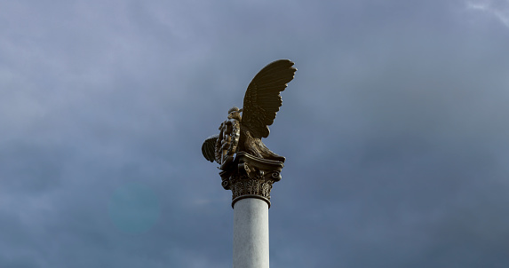 The majestic atmosphere of the monument to sinking ships against the sky in sunlight from a low angle. Monument to sunken ships in Crimea with a double-headed eagle holding a laurel wreath with an anchor close-up.