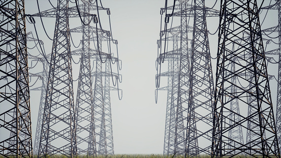 A road overgrown with grass runs between power lines. Endless rows of power lines in thick fog stretching to the horizon