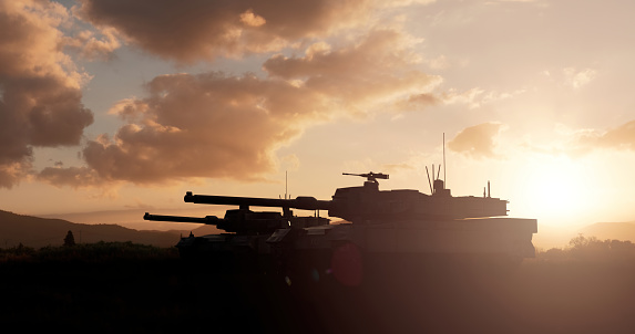 Armored troops in the field at sunset. Silhouettes of military tanks against the sunset sky. Armored troops in the field at sunset, we see tanks from the side