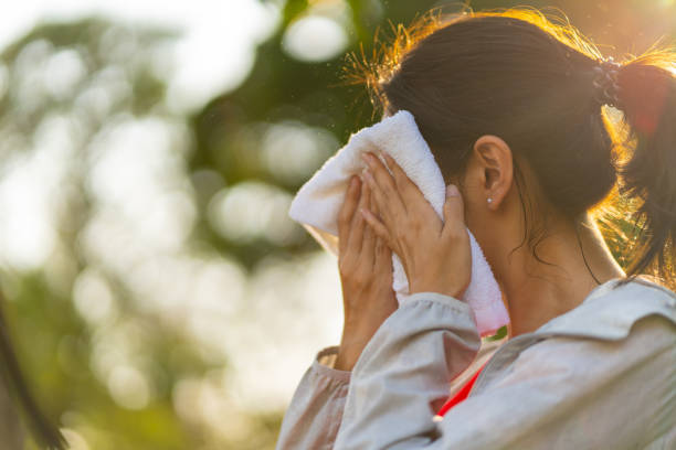 公園でのジョギング運動中にタオルで顔の汗を拭くアジア人女性。 - 汗 ストックフォトと画像
