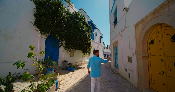 Man walking among blue and white houses Sidi Bou Said, Tunisia. Traditional town streets.