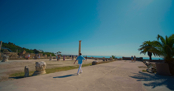 Tourist man visiting Ruins of ancient Carthage in Tunisia. Ancient archaeological site. Historical excursion in ancient city. Sights of Tunis.