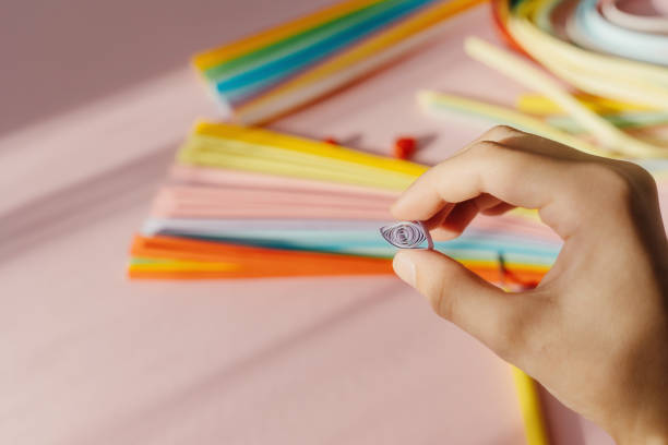 istock Paper and quilling tools on a pink background with hands and space for text and design. 1474983149