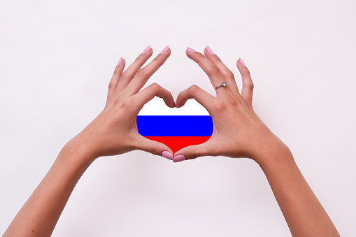 the flag of Russia. A woman makes a heart with her hands. the flag of Russia in his hands. the concept of love for russia