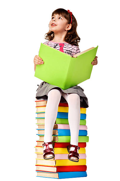 Little girl sitting on stack of books. Isolated over white