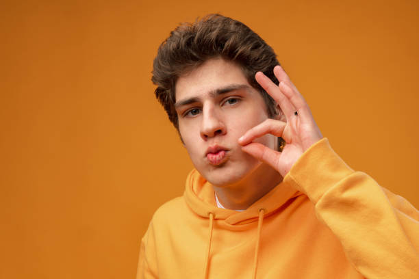 istock Young man hushing at camera and telling to be quiet on yellow background 1474986083