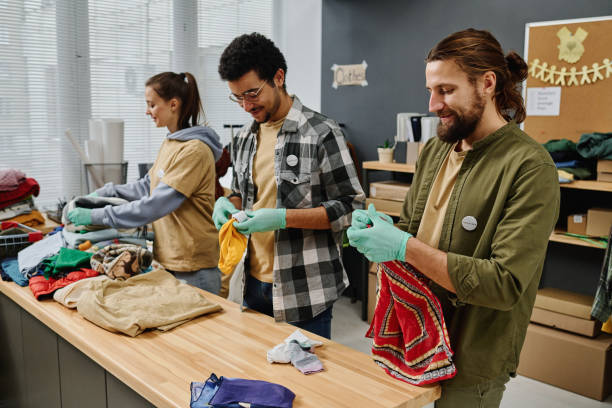 istock Row of young intercultural people sorting second hand clothes 1474989519