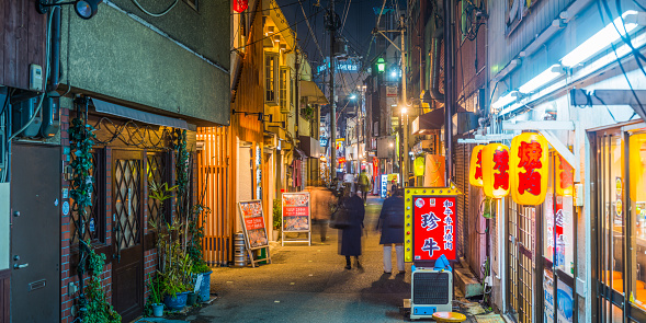 People strolling through the neon drenched alleyways of restaurants and bars at night in the Juso district of Osaka, Japan’s vibrant second city.